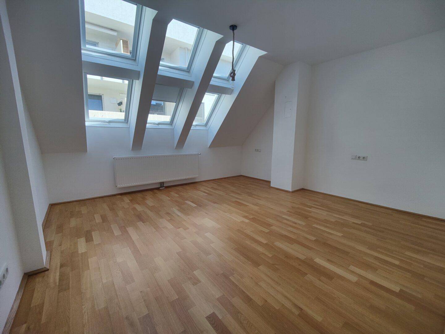 Geräumiger Dachgeschossraum mit Parkettboden, mehreren Dachfenstern und viel Tageslicht.