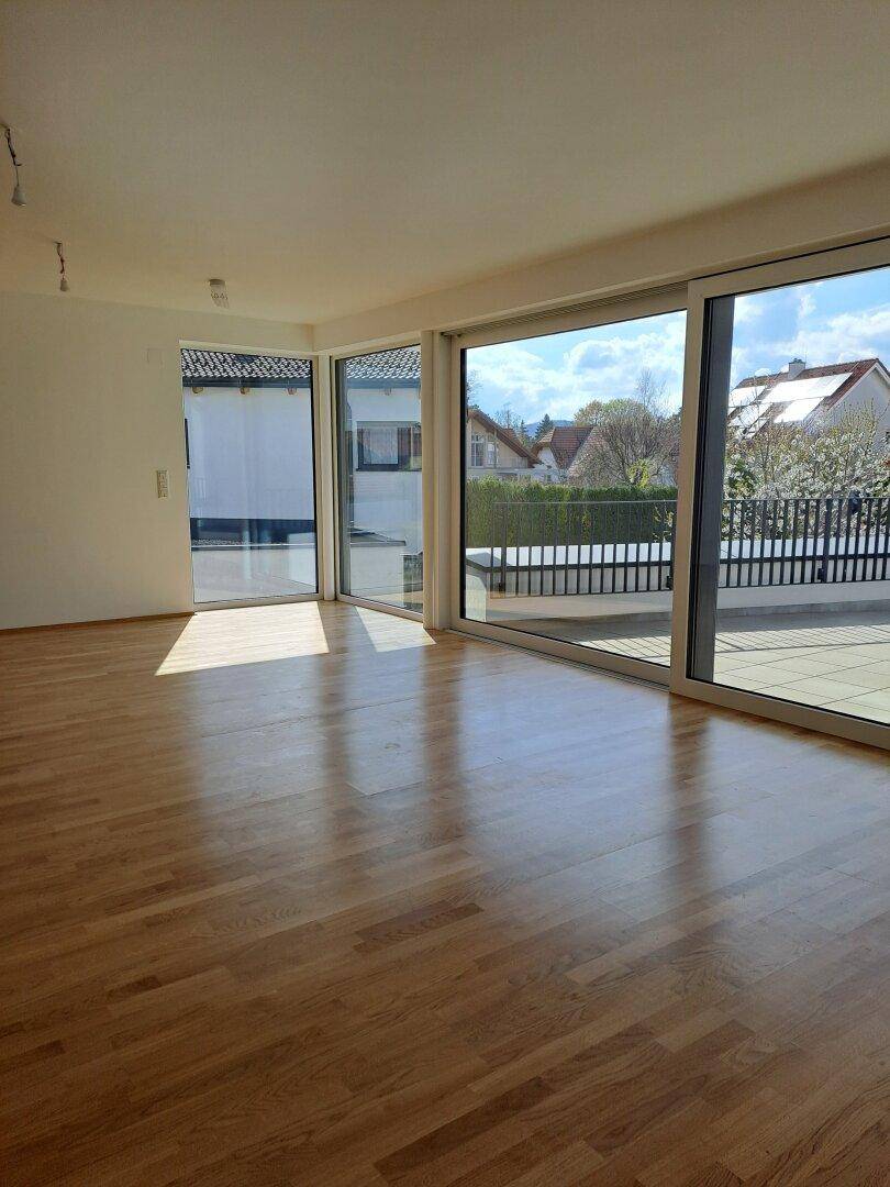 Lichtdurchfluteter Wohnbereich mit Holzplankenboden und großen Schiebetüren zur Terrasse.