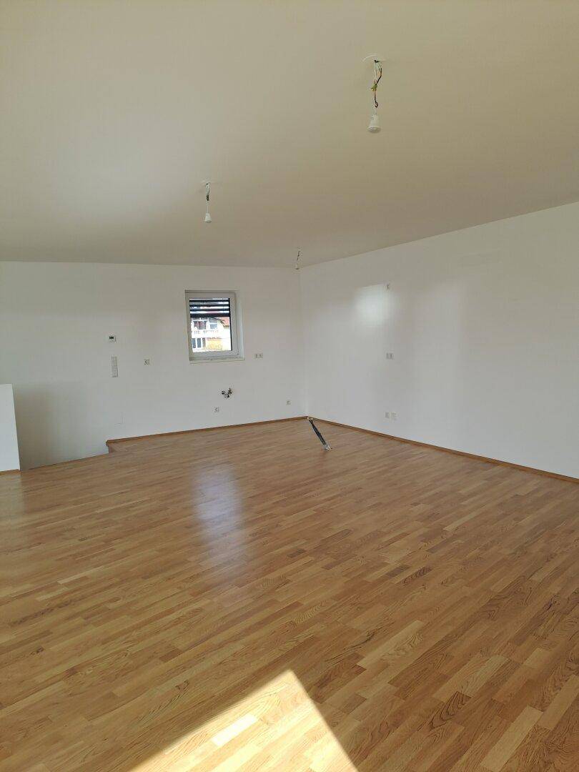 Heller, leerer Raum mit neuem Holzplankenboden und weiß gestrichenen Wänden.