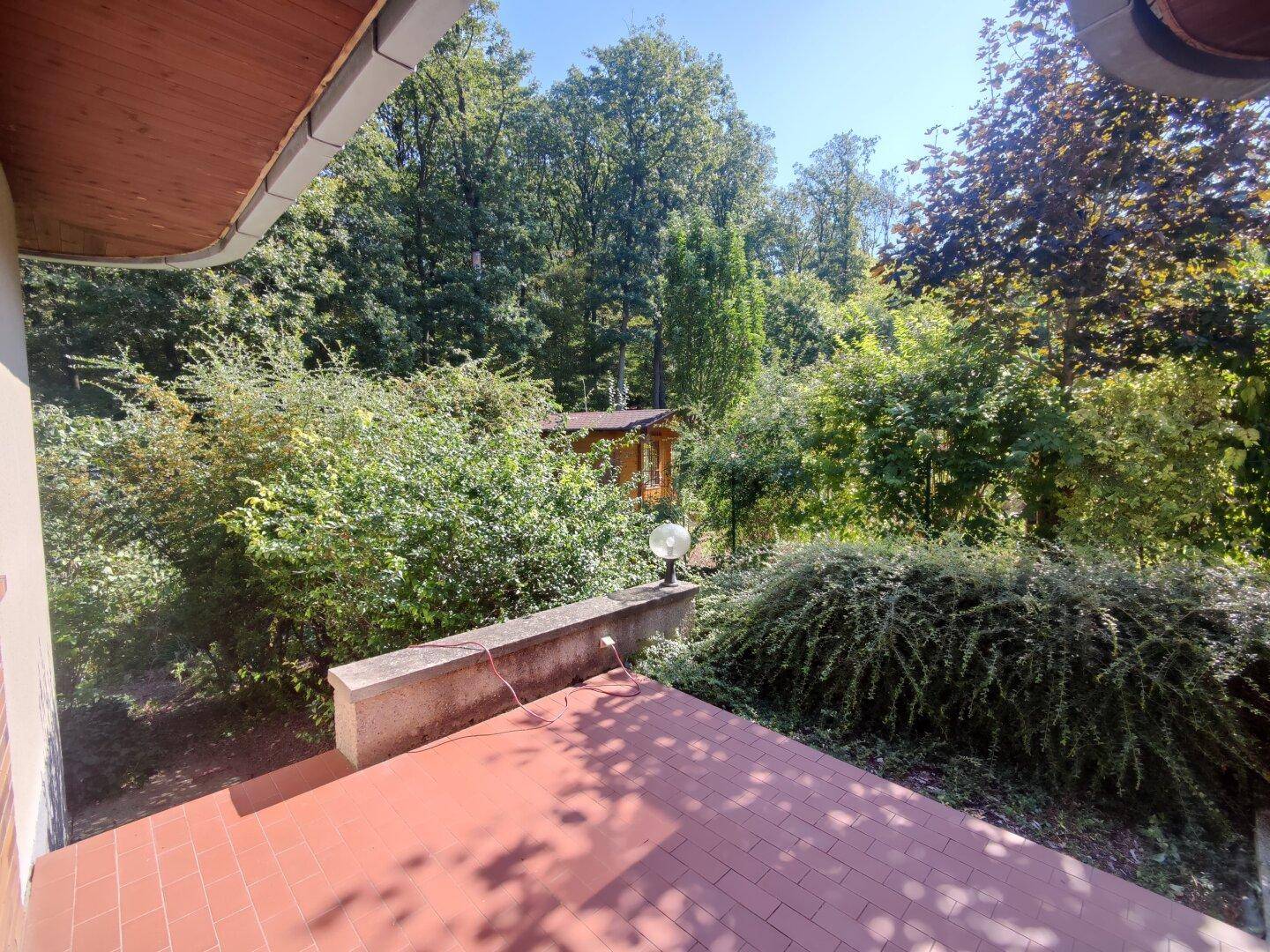 Terrasse mit Terrakottafliesen und weitem Blick in den üppigen, grünen Garten.