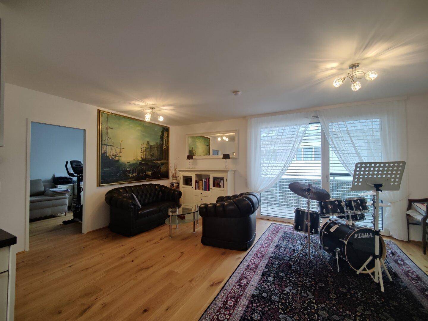 Helles Wohnzimmer mit Holzboden, bequemen Ledersofas und einem Schlagzeug.