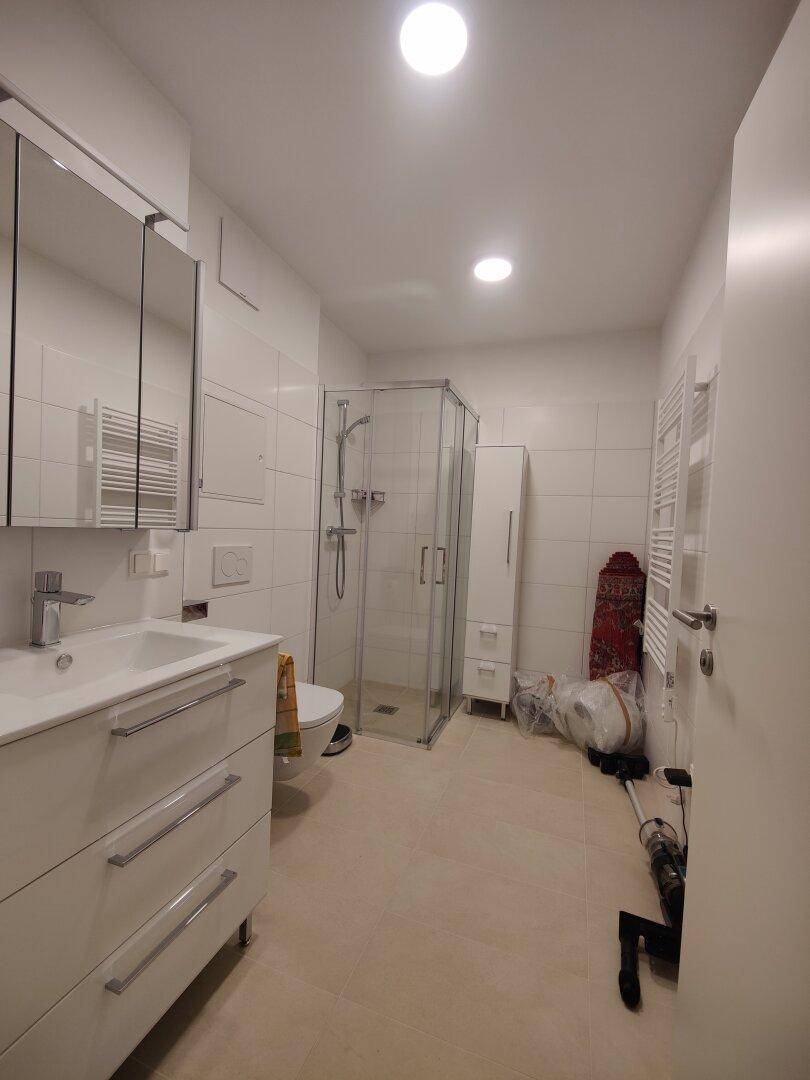 Modernes Badezimmer mit Dusche, Waschbecken, WC und beheiztem Handtuchhalter.