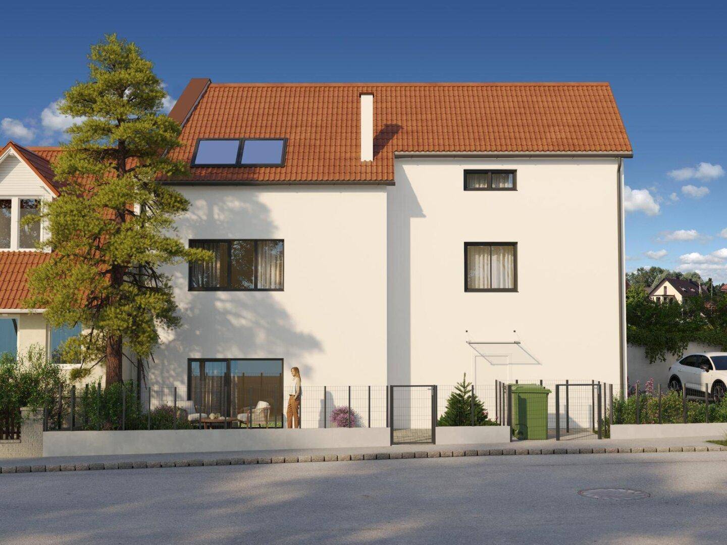 Seitenansicht des Neubaus mit weißer Fassade, Satteldach und kleinen Gartenflächen.