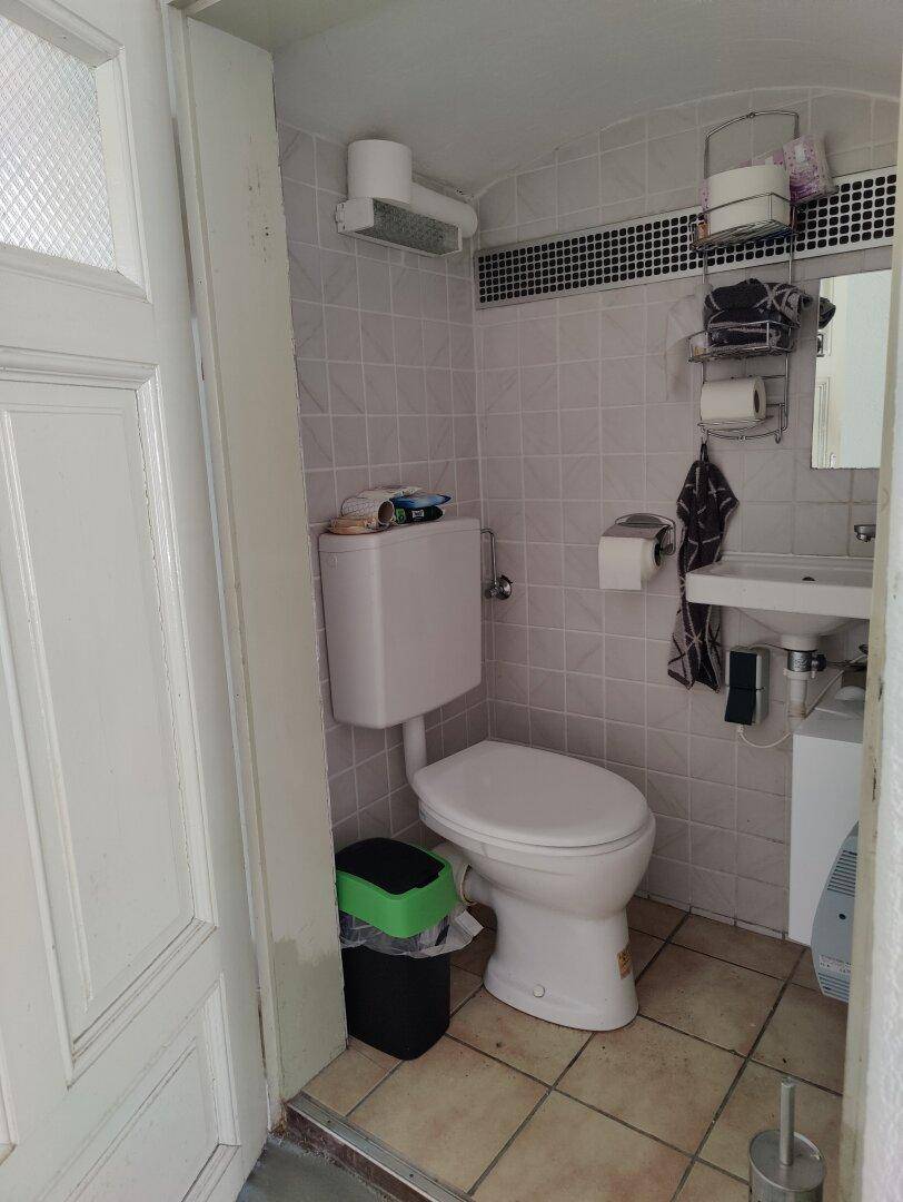 Kleines WC mit Fliesenboden, Wandfliesen und einem einzelnen Waschbecken.
