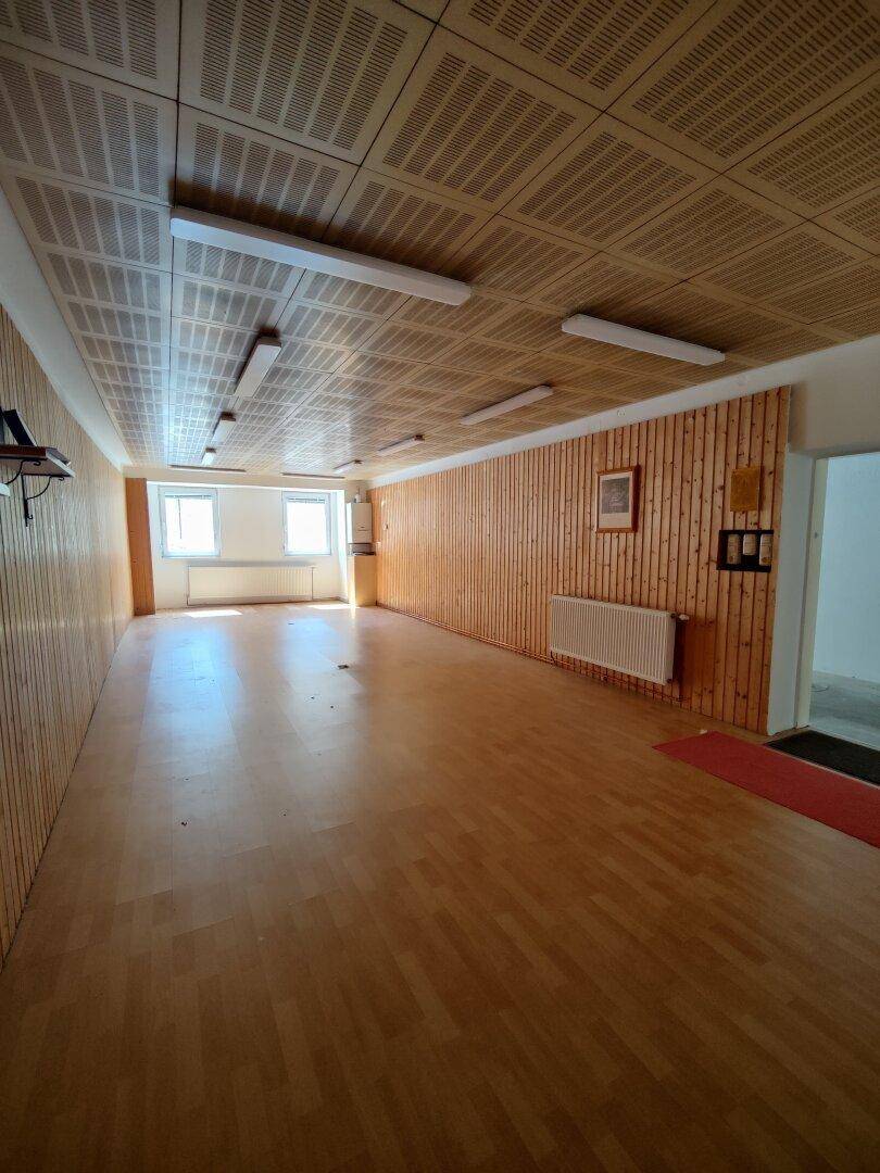 Geräumiger Raum mit Holzvertäfelung an Wänden und Decke sowie hellem Holzboden.