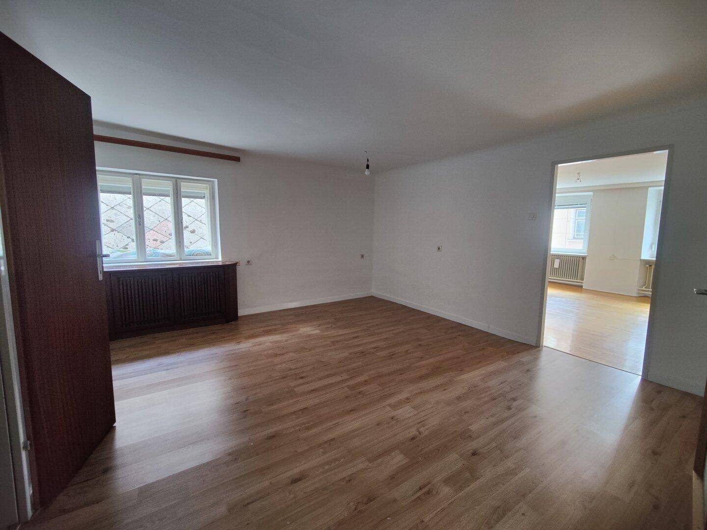 Geräumiger, heller Raum mit Laminatboden und Blick auf die Umgebung.