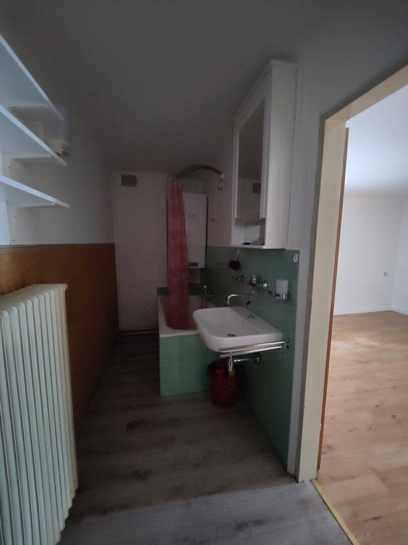 Badezimmer mit Waschbecken, Badewanne und einfacher Einrichtung.
