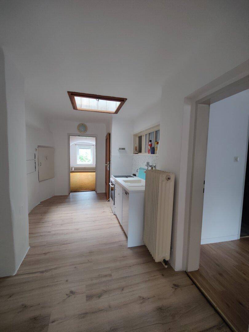 Heller Flur mit kleiner Küchenzeile, Laminatboden und Oberlicht.