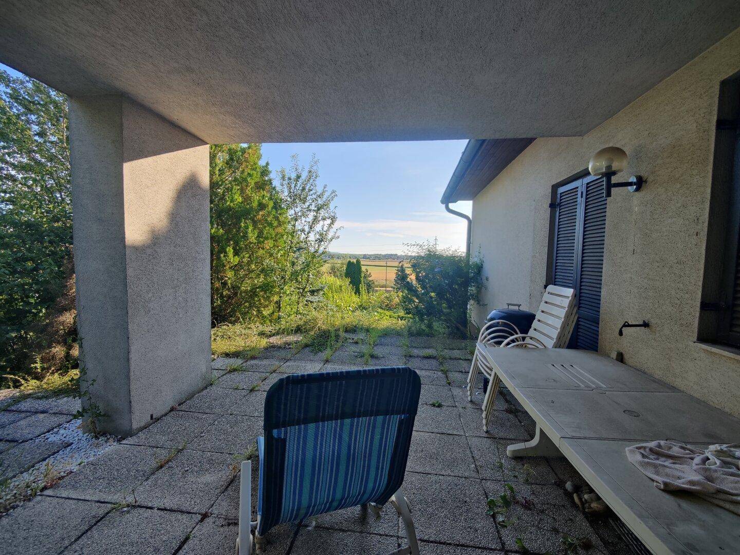 Überdachte Terrasse mit Sitzgelegenheiten und weitem Blick über die Landschaft.