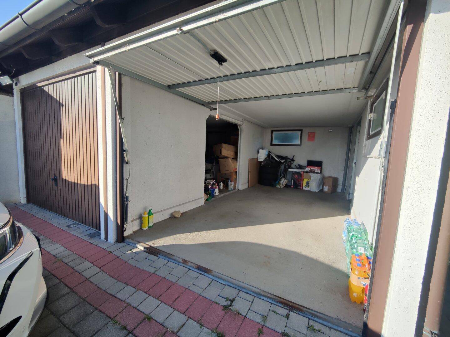 Geräumige Garage mit offenem Tor, gepflasterter Einfahrt und Stauraum.