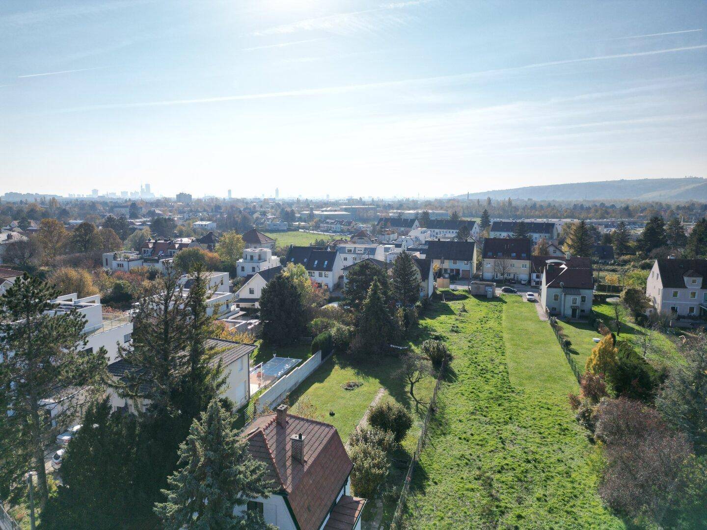 Weitläufige Luftaufnahme einer Wohnsiedlung mit viel Grünfläche und Blick auf die Stadt in der Ferne.