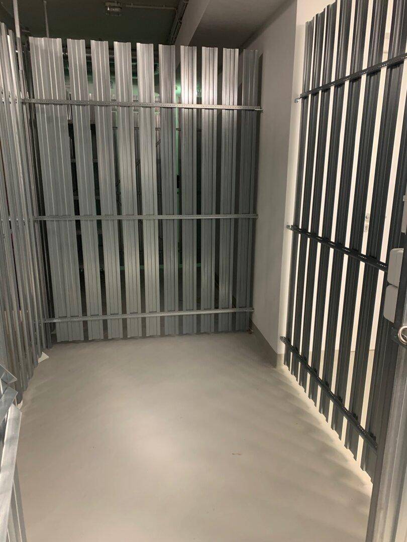 Abgetrennter Lagerraum mit Metallwänden und Betonboden, ideal für zusätzlichen Stauraum.