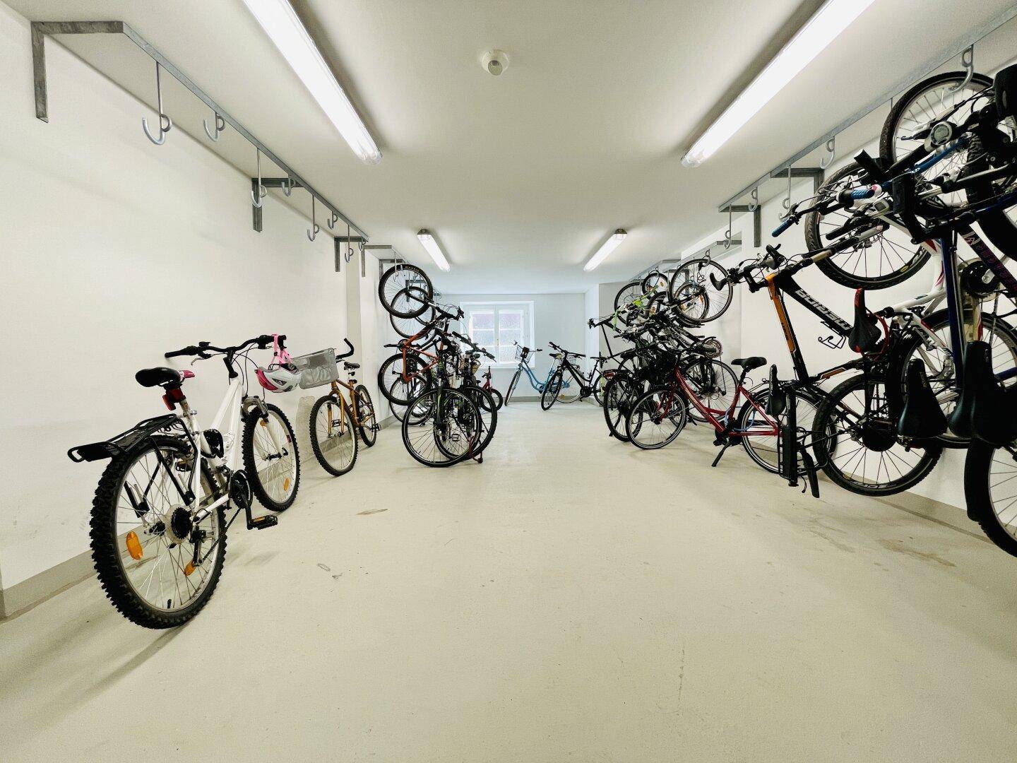 Geräumiger Fahrradraum mit vielen Fahrrädern und Aufhängemöglichkeiten an den Wänden.