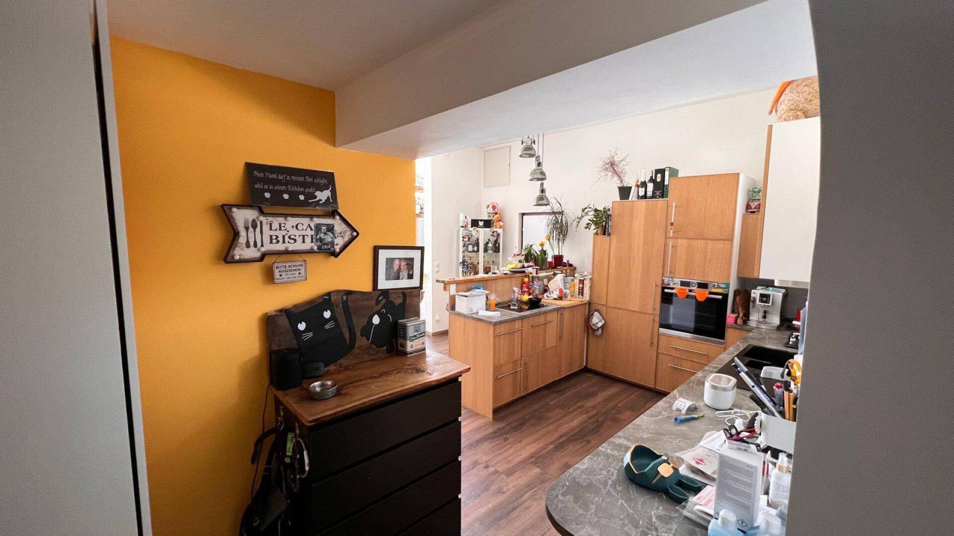 Funktionale Küche mit Holzschränken, integrierten Geräten und einer gelben Akzentwand.