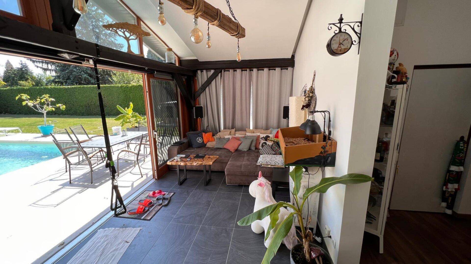 Gemütliches Wohnzimmer mit großem Sofa, Blick auf den Pool und Zugang zur Terrasse.
