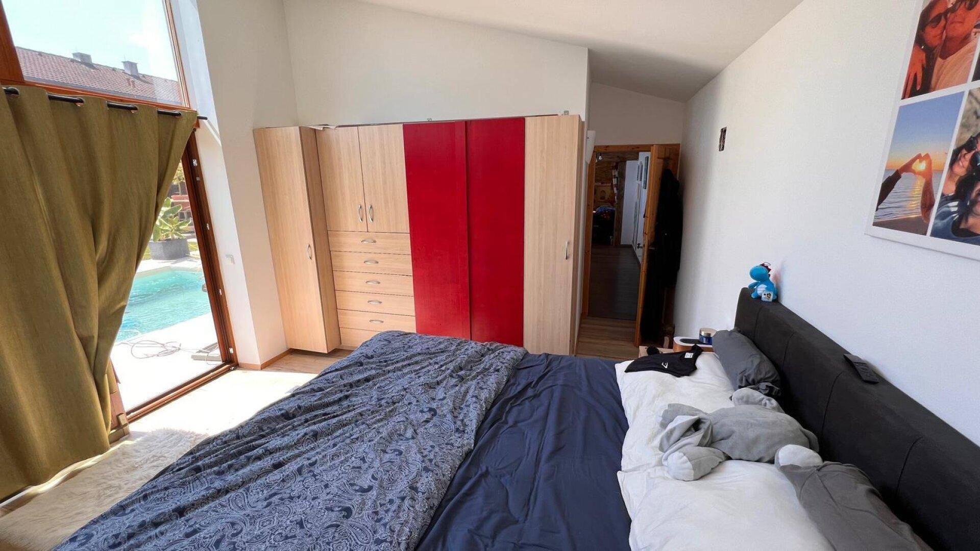 Schlafzimmer mit Doppelbett, Einbauschränken und großen Fenstern mit Poolblick.