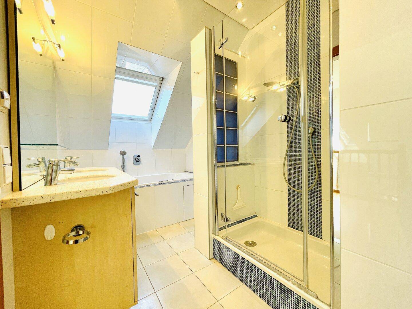 Modernes Badezimmer mit Duschkabine, Badewanne, Waschtisch und Dachfenster.