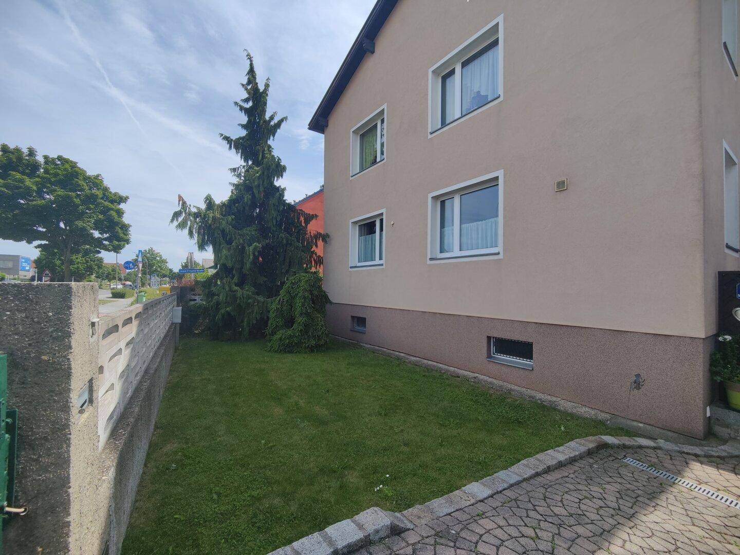 Seitlicher Gartenbereich mit Rasenfläche und gepflastertem Zugang zum Haus.