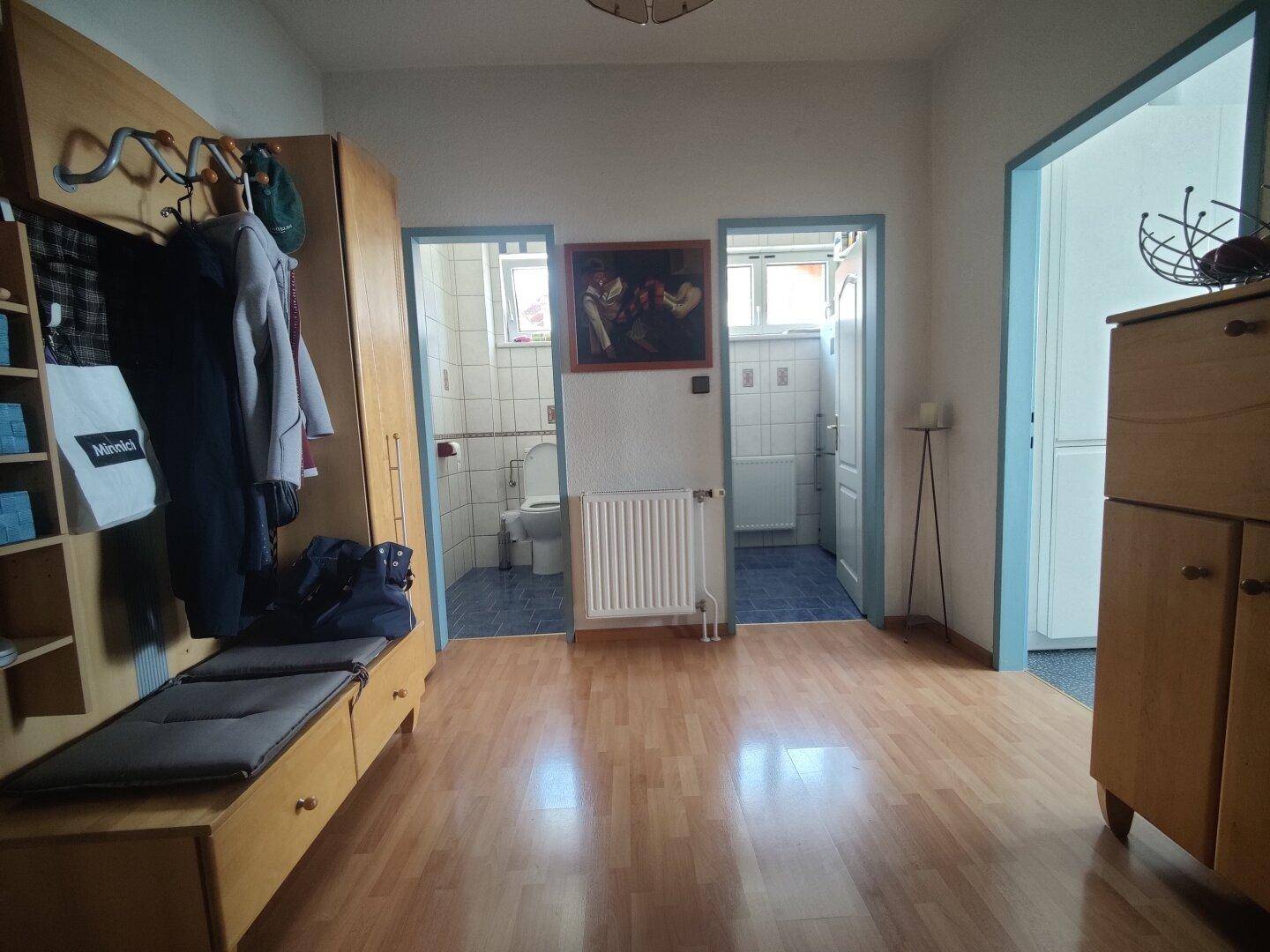 Heller Flur mit Holzfußboden und Zugang zu zwei Badezimmern oder WCs.