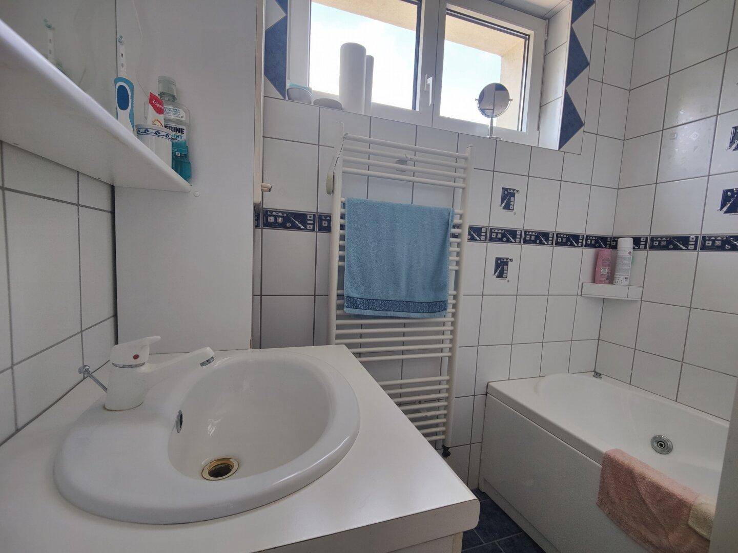 Detailansicht des Badezimmers mit Waschbecken, Badewanne und beheiztem Handtuchhalter.