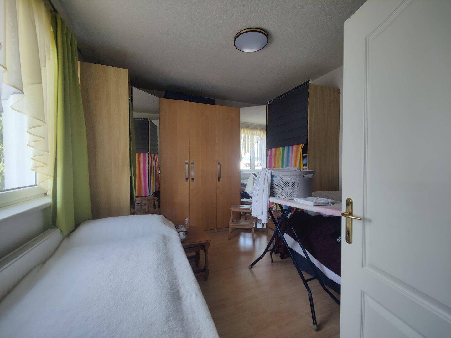 Helles Schlafzimmer mit Einzelbett, Kleiderschränken und Fenster, als Gästezimmer nutzbar.