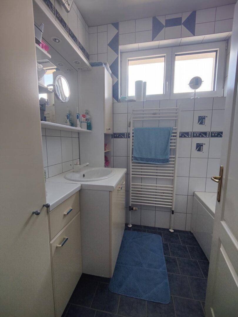 Badezimmer mit Badewanne, Waschbecken, beheiztem Handtuchhalter und Fenster.
