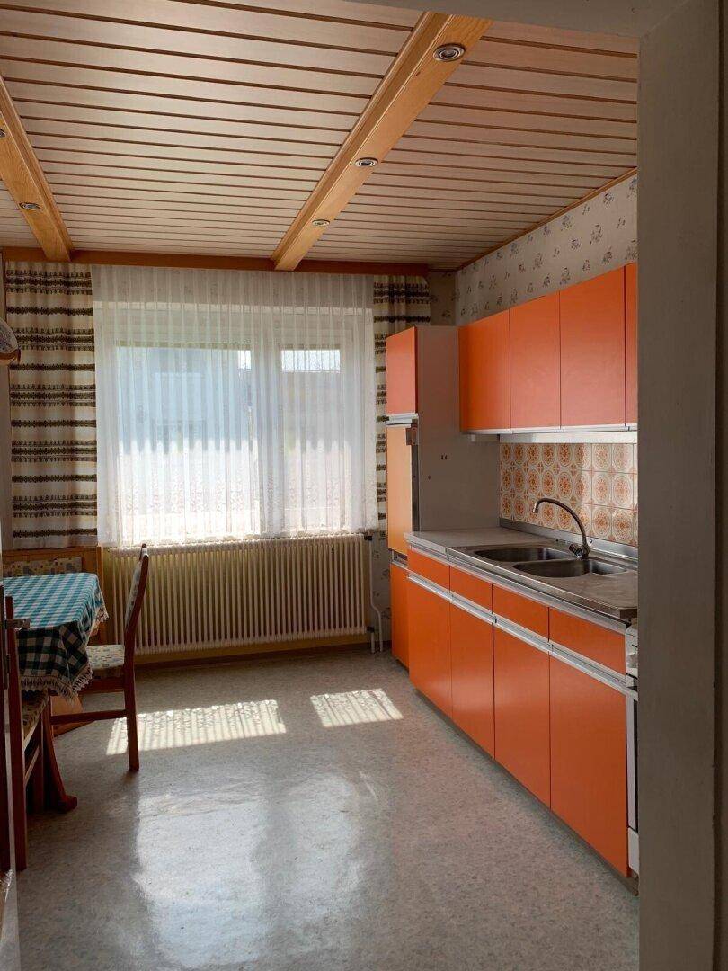 Helle Küche im Vintage-Stil mit orangefarbenen Schränken und Holzdecke.