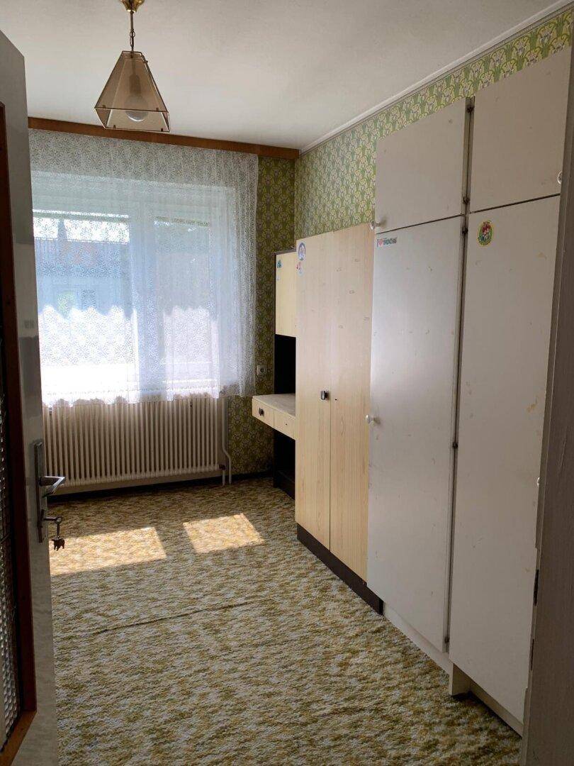 Schlafzimmer mit Teppichboden, gemusterter Tapete und Einbauschränken.