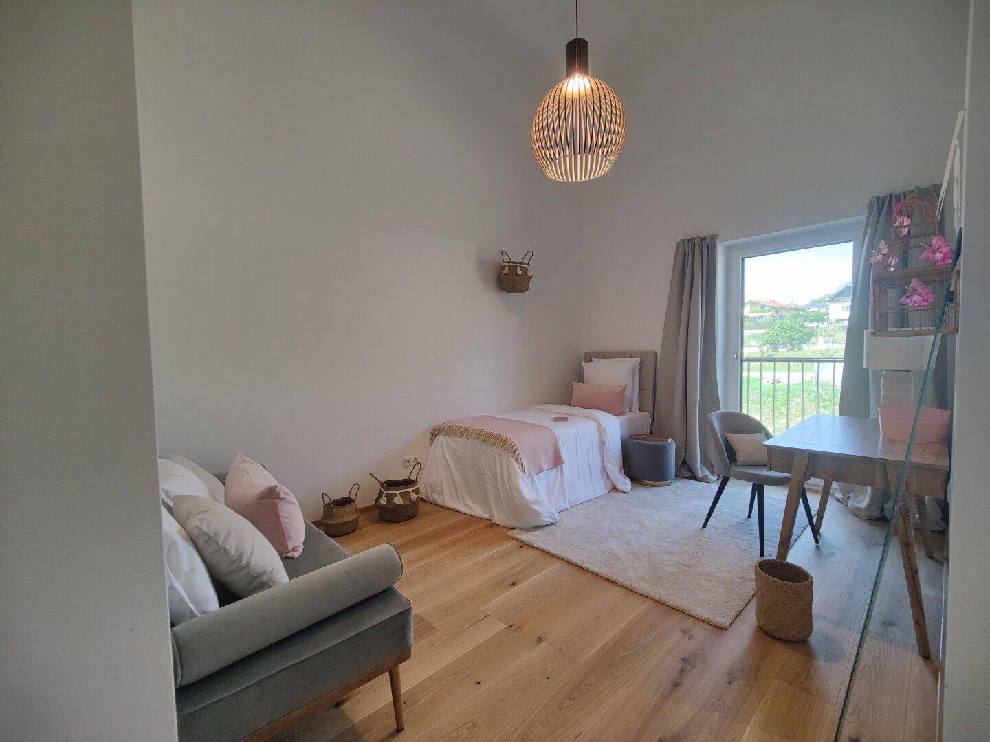 Helles Kinderzimmer mit Holzboden, Einzelbett und Schreibtisch am Fenster.