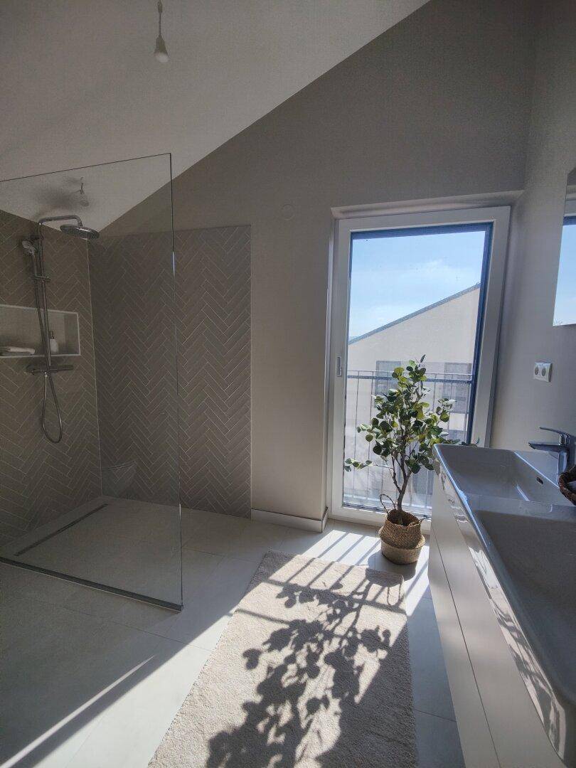 Modernes Badezimmer mit großer begehbarer Dusche, Doppelwaschbecken und Fenster.