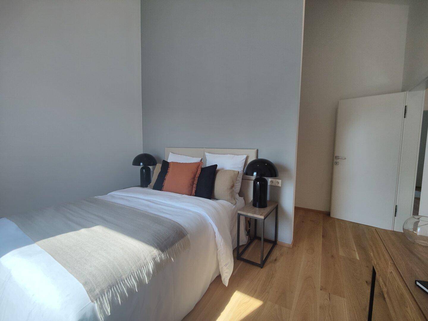 Modernes Schlafzimmer mit Holzboden, Doppelbett und stilvollen Nachttischen.