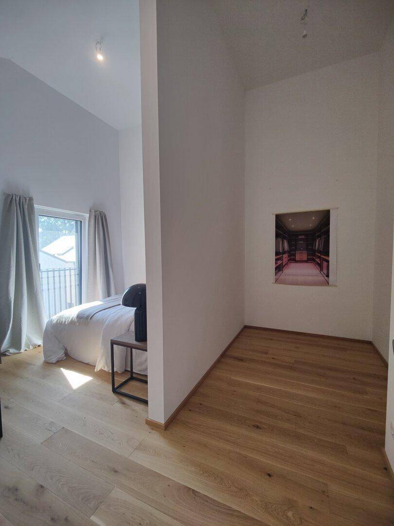 Helles Schlafzimmer mit Holzboden, Balkonzugang und minimalistischer Einrichtung.