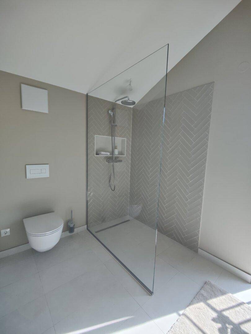 Modernes Badezimmer mit begehbarer Dusche, Wand-WC und hellen Fliesen.