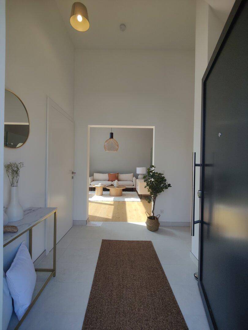Heller Eingangsbereich mit Fliesenboden, moderner Konsole und Blick in den Wohnbereich.