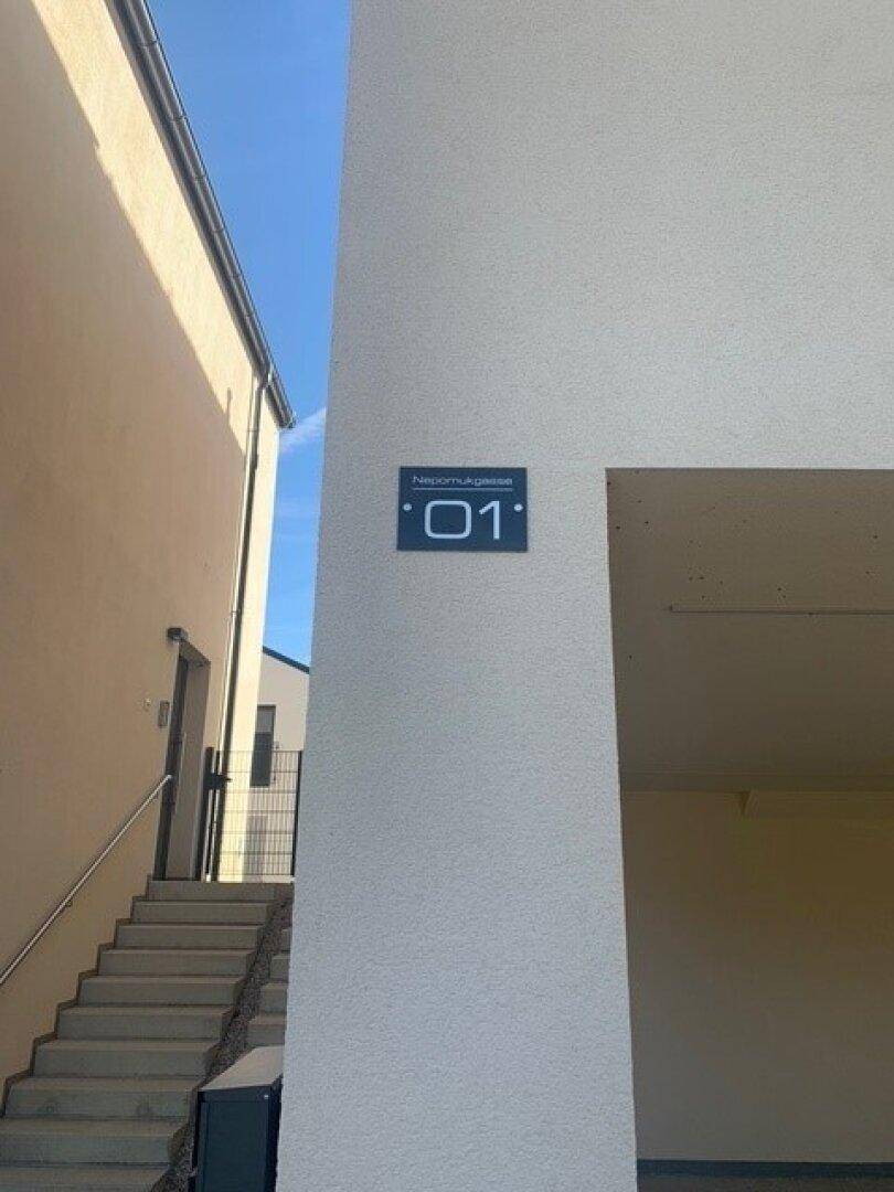 Außenansicht eines modernen Hauses mit Treppenaufgang und Hausnummer.