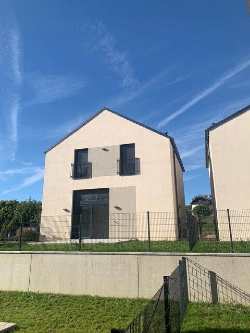 Moderne Doppelhaushälfte mit schlichter Fassade und kleinen Balkonen.
