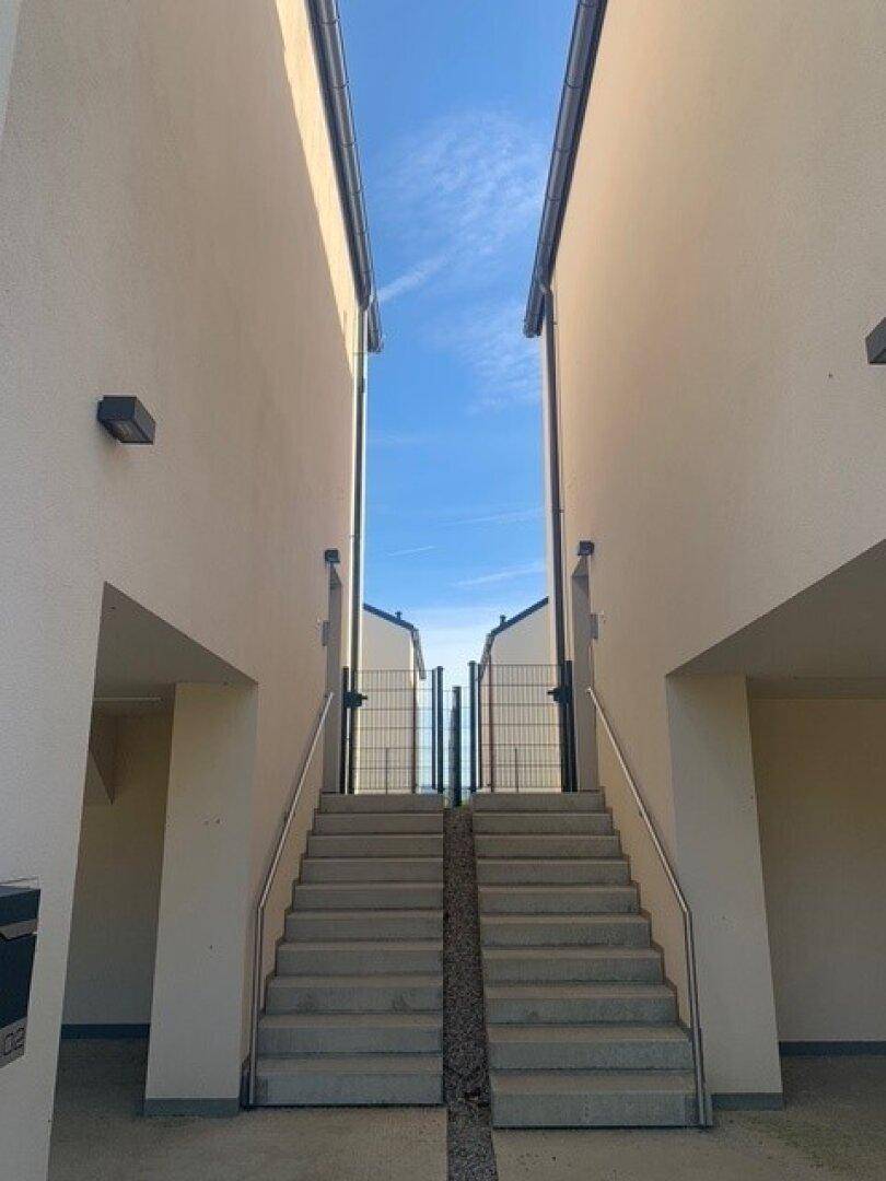 Außentreppe zwischen zwei Gebäuden mit Metallgeländer und Zugang zum oberen Bereich.