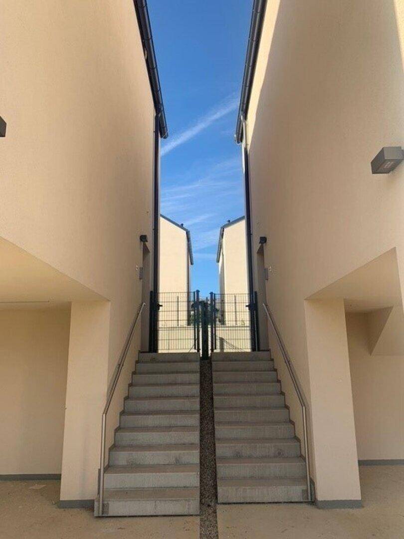 Zugangsbereich mit Treppe zwischen zwei Gebäuden, führt zu den oberen Etagen.