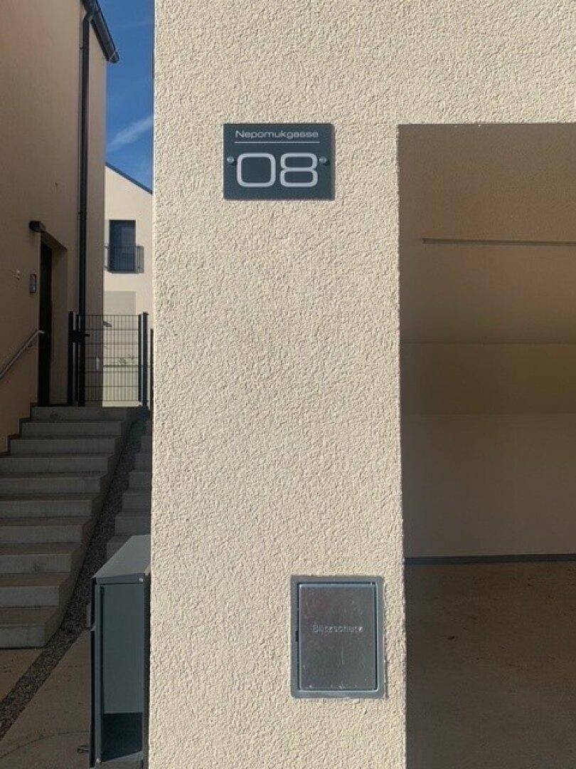 Hausnummer und Straßenname an der modernen Fassade des Gebäudes.