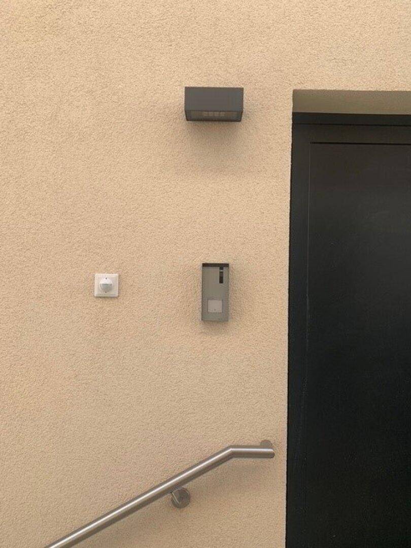Fassade mit Außenleuchte, Bewegungsmelder und Handlauf am Treppenaufgang.