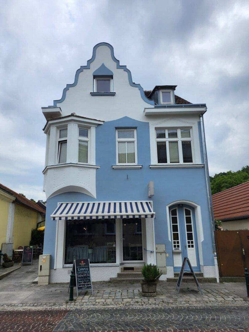 Charmantes Gebäude mit hellblauer Fassade, weißen Akzenten und einem gestreiften Vordach.