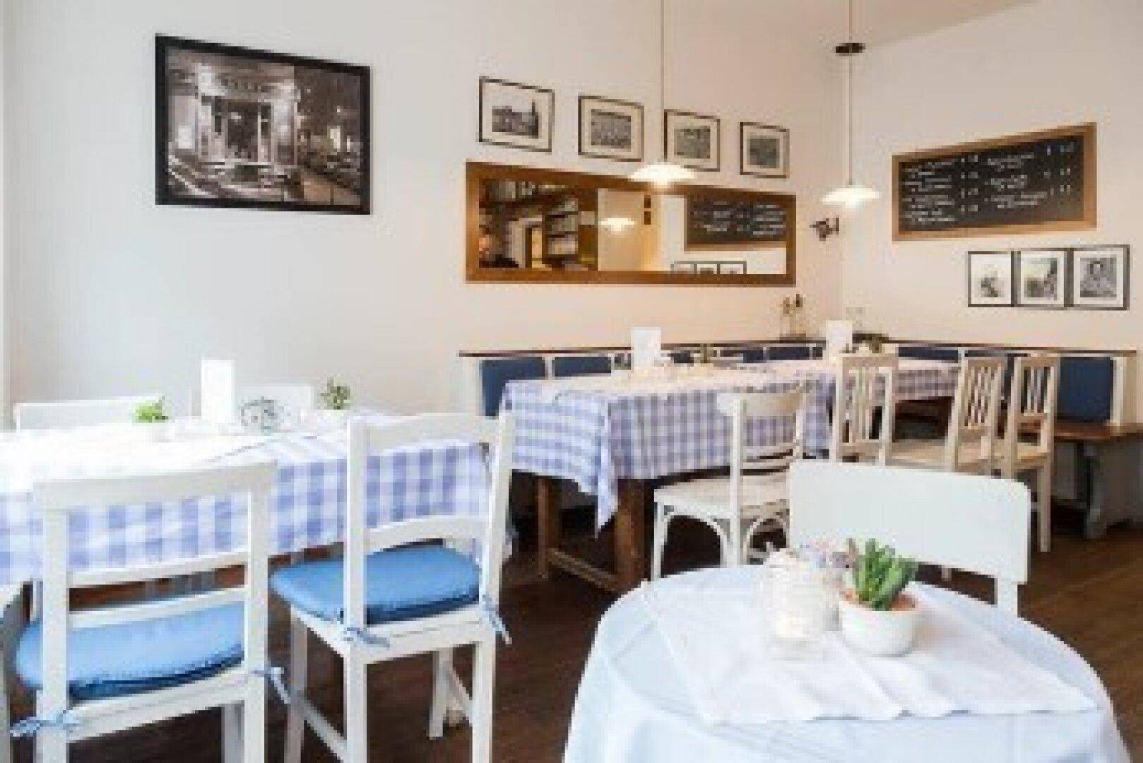 Gemütlicher Restaurantbereich mit karierten Tischdecken, Holzboden und traditioneller Einrichtung.