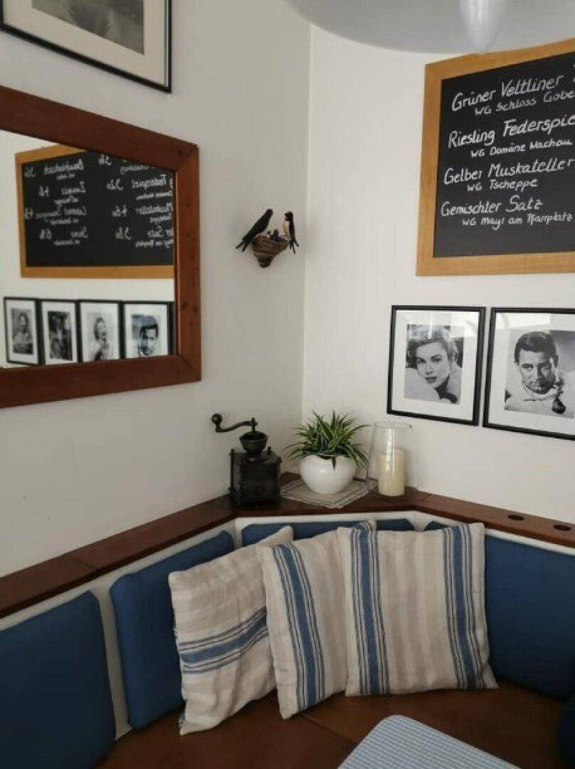 Detailansicht einer gemütlichen Sitzecke mit blauen Polstern, Kissen und einer Tafel mit Angeboten.