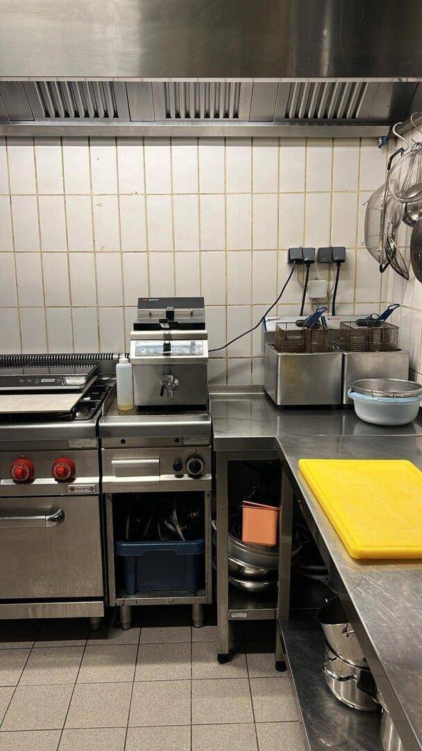 Professionelle Küche mit Fritteusen, Kochfeldern und Edelstahlarbeitsflächen für den Gastronomiebedarf.