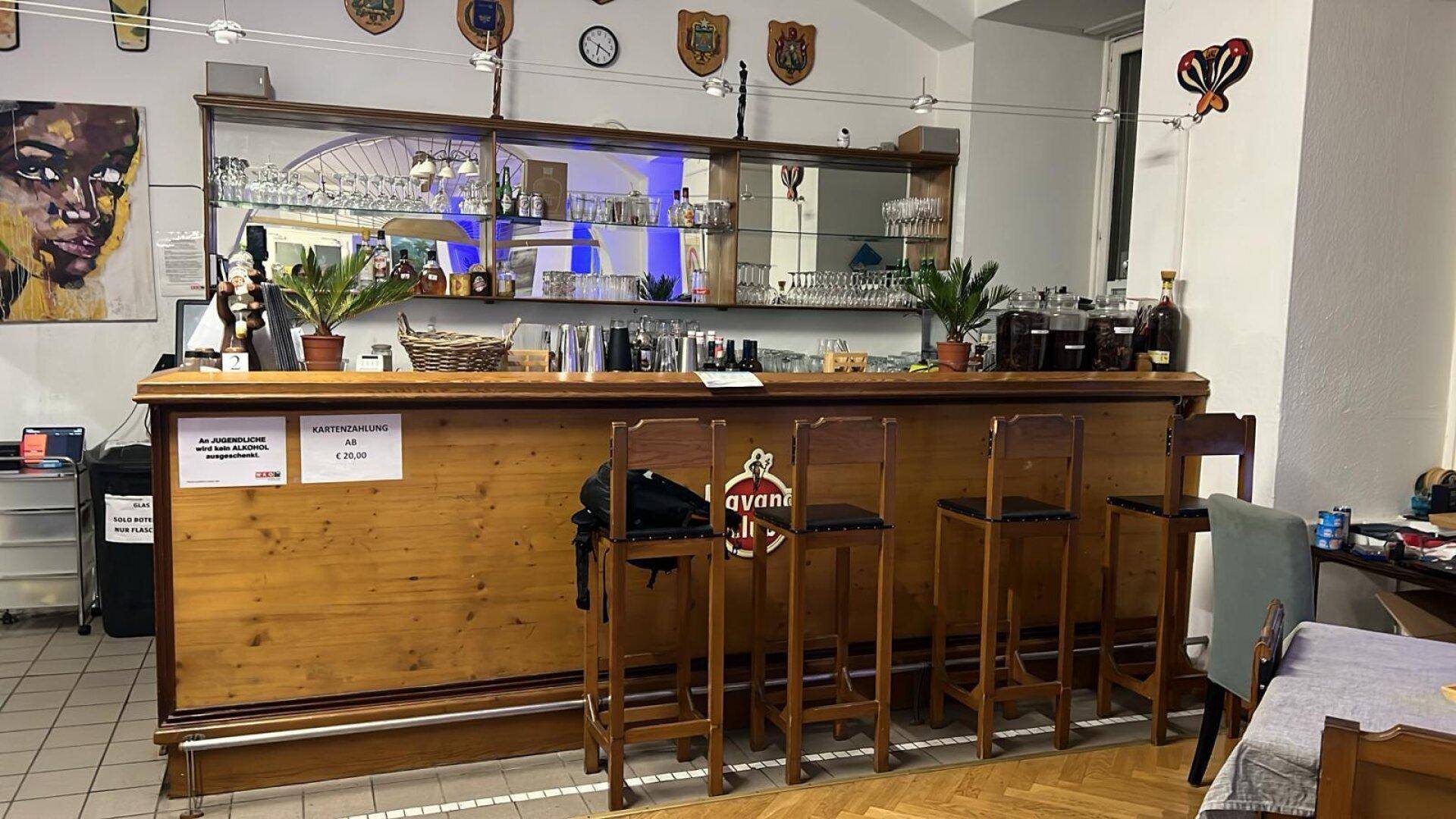 Barbereich mit Holztheke, Barhockern und Spiegelrückwand, gut ausgestattet für Getränkeservice.
