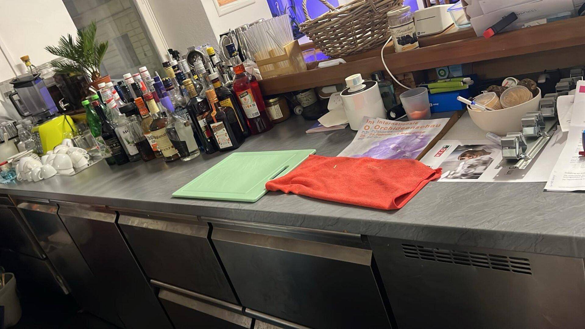 Nahaufnahme der Bartheke mit Getränken, Gläsern und Arbeitsflächen, bereit für die Zubereitung von Cocktails.