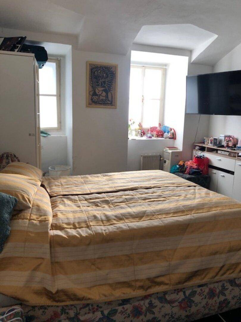 Schlafzimmer mit Bett, zwei Fenstern, Fernseher und Kleiderschrank.