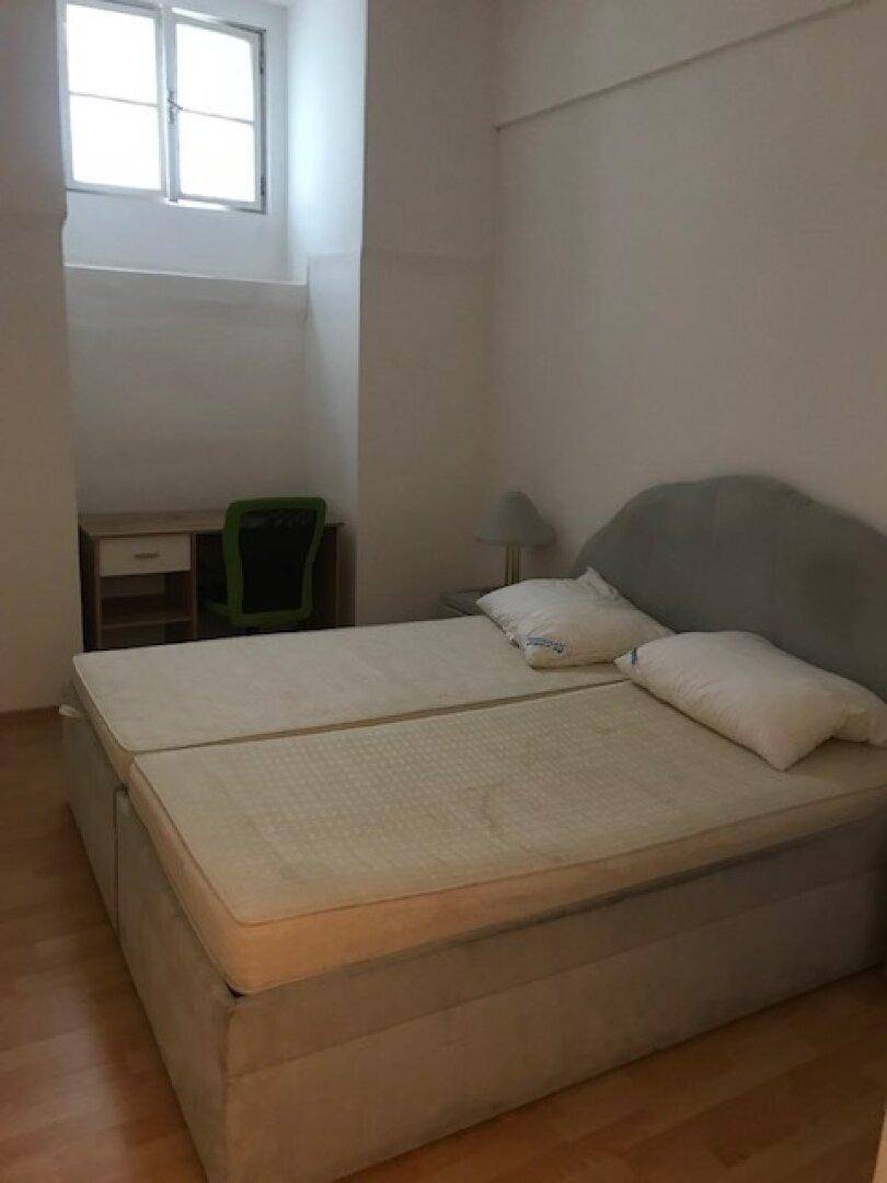 Schlafzimmer mit Bett, Fenster, Schreibtisch und hellem Laminatboden.