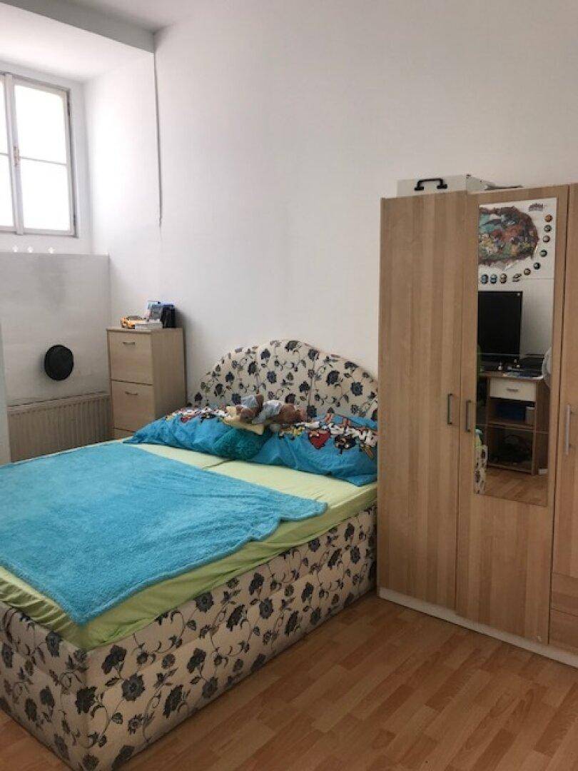 Schlafzimmer mit Bett, Kleiderschrank mit Spiegel und hellem Laminatboden.