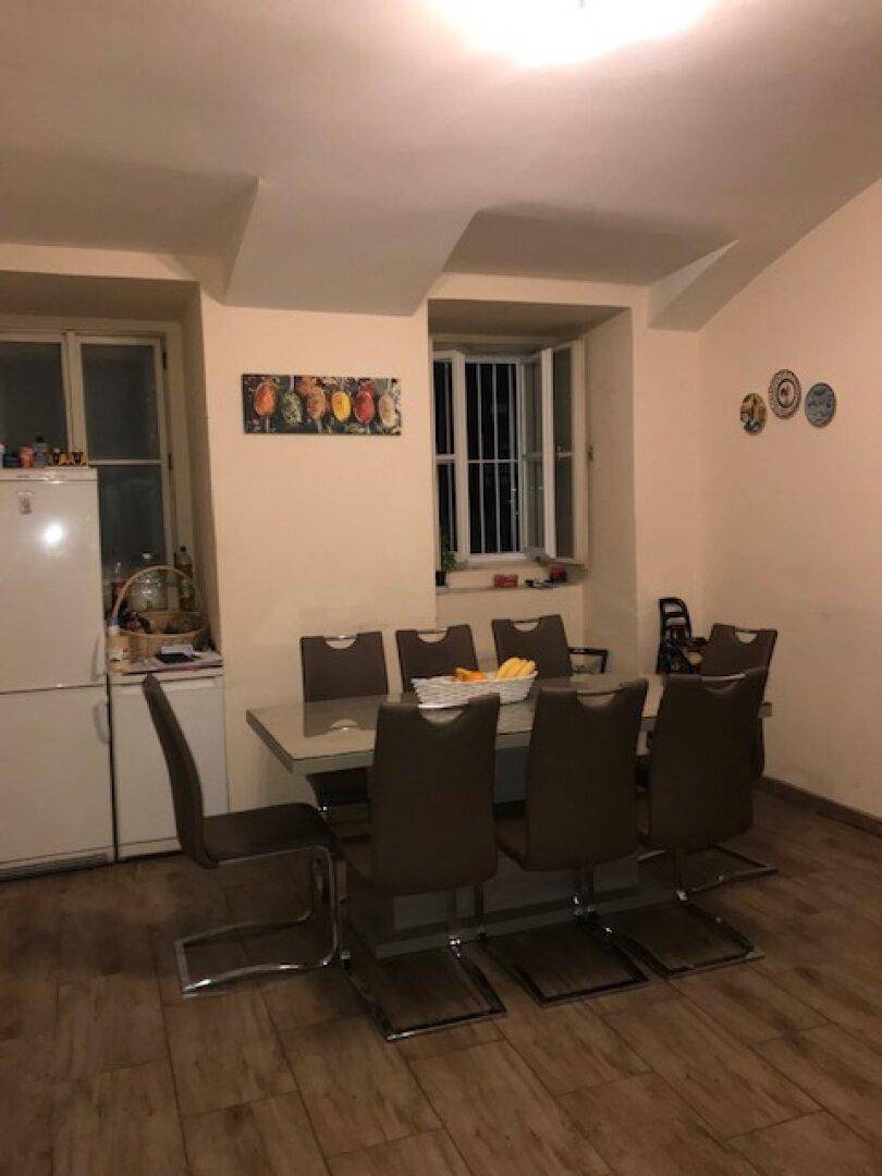 Esszimmer mit großem Esstisch, Stühlen, Fenster und einem Kühlschrank mit Gefrierfach.